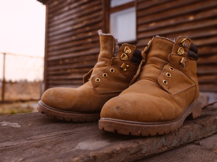 Botas de gamuza junto a cabaña rústica