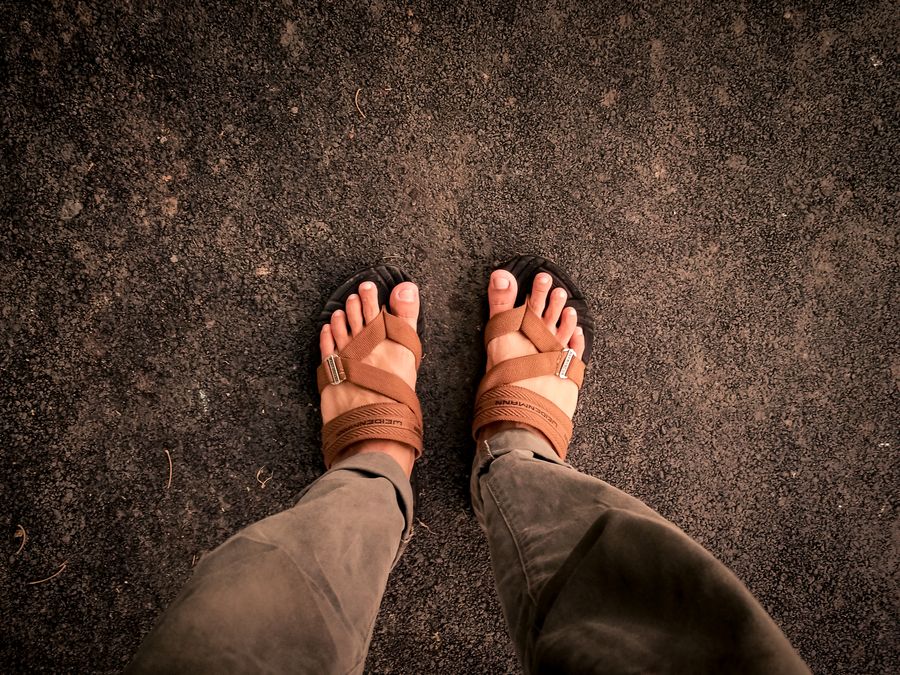 Turista con sandalias en playa negra